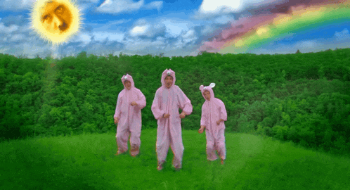 three people in pink bunny suits are dancing in the grass