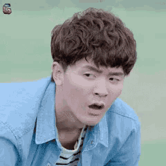 a young man in a blue denim jacket is making a surprised face .