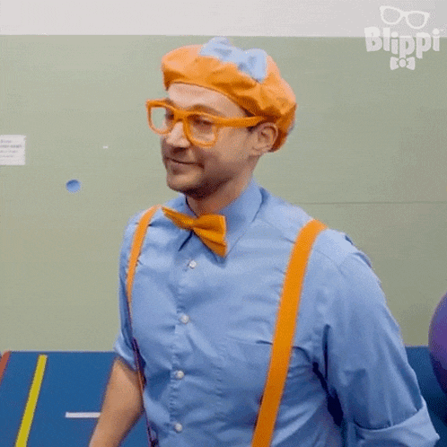 a man wearing a blue shirt , orange suspenders , a bow tie and a beret is smiling .