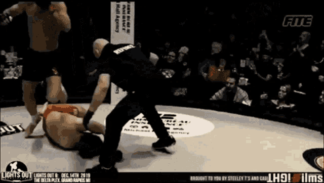a fighter is laying on the ground in a boxing ring while a referee stands behind him