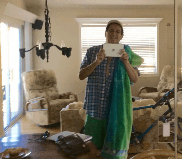 a man in a plaid shirt is taking a picture of himself in a mirror