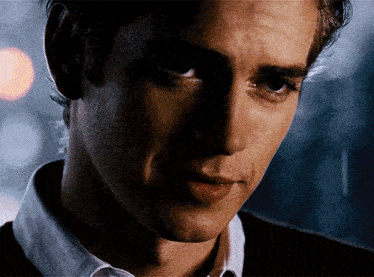 a close up of a man 's face with a white shirt on