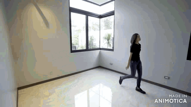 a woman is running in an empty room with a large window .