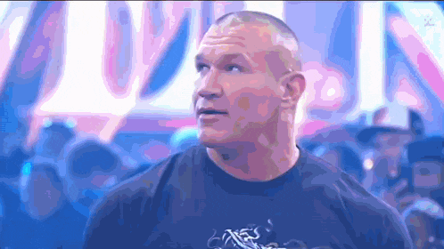 a man in a black t-shirt is standing in front of a crowd .