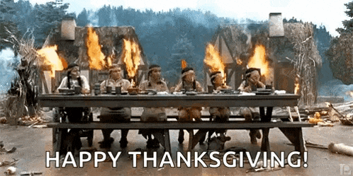 a group of people are sitting at a table with flames coming out of it and the words `` happy thanksgiving '' .