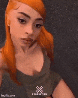 a woman with red hair is taking a selfie in a green tank top and shorts .