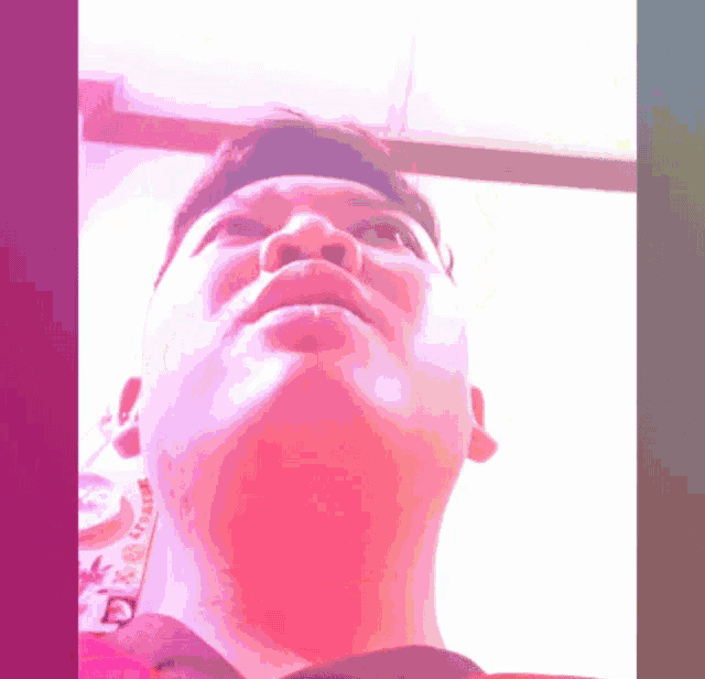 a close up of a man 's face with a purple and pink background