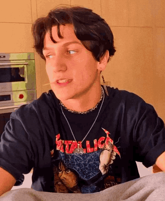 a young man wearing a black metallica t-shirt and a necklace
