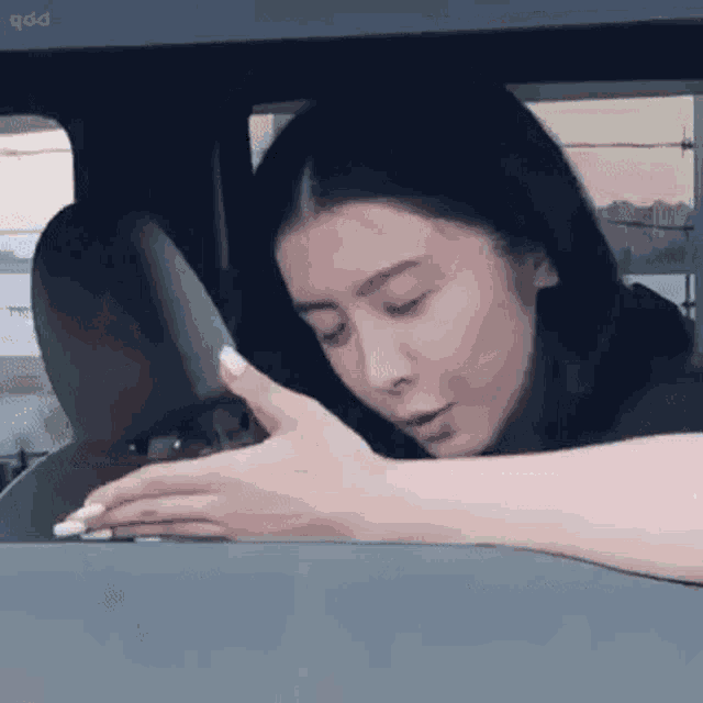 a woman is sitting in the driver 's seat of a car and touching the dashboard .