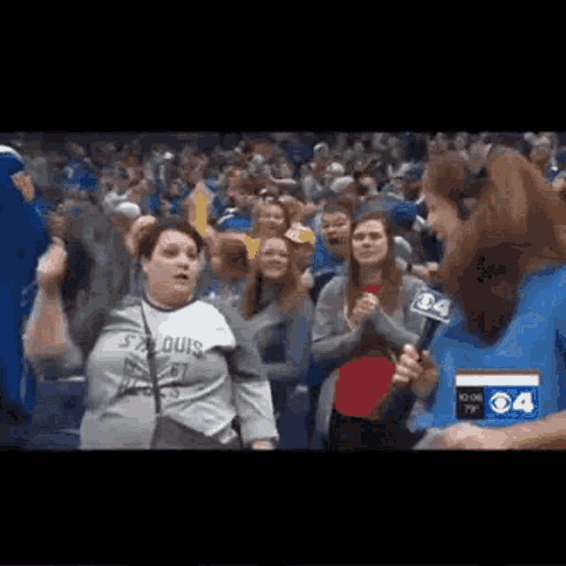a woman is holding a microphone in front of a crowd of people at a sports game .