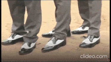 a group of men wearing black and white shoes are dancing together .