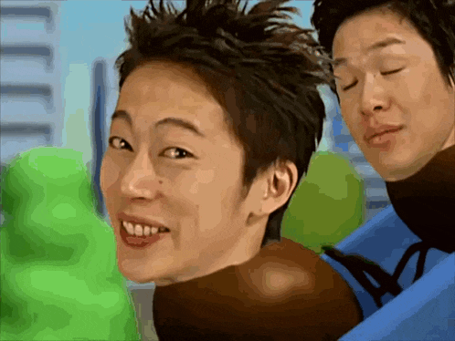 a man with short hair is smiling next to a man with long hair
