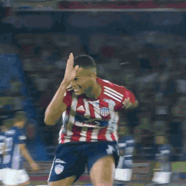 a soccer player wearing a red and white striped jersey with the word adidas on it