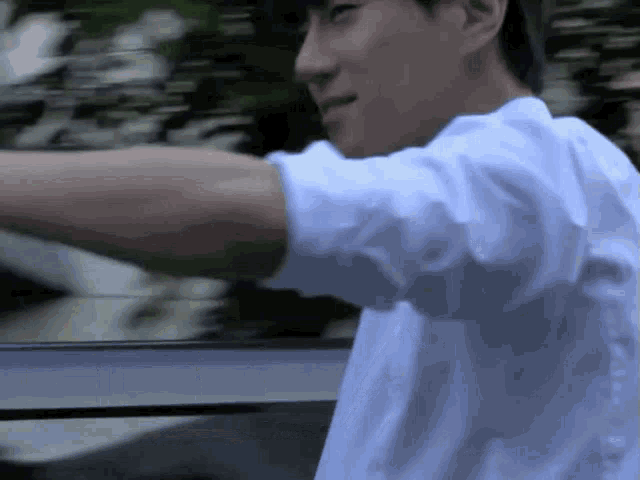 a man wearing a white shirt is standing in front of a window