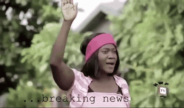 a woman wearing a pink headband is waving her hand in the air .