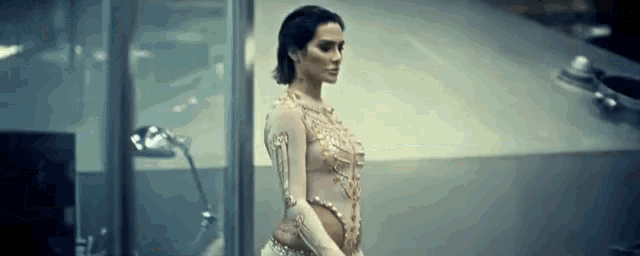 a woman in a gold dress is standing in front of a building .