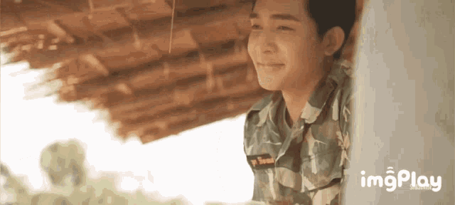 a man in a military uniform is smiling and looking out of a window .