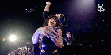a man and a woman are hugging on a stage with the number 20j on the bottom right