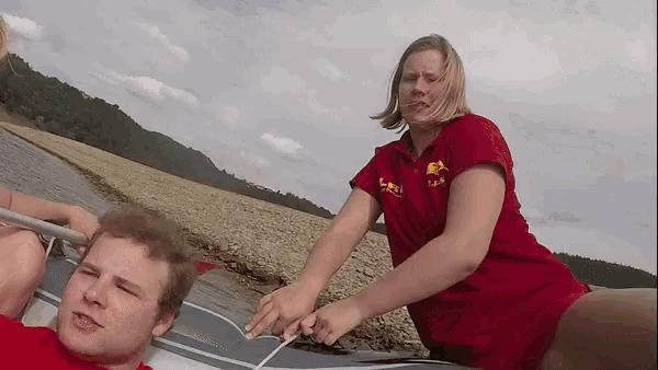 a woman in a red shirt that says lifeguard pulls a man in a raft