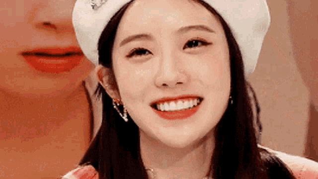 a close up of a woman wearing a white beret smiling .
