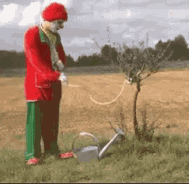 a clown is watering a tree with a hose .