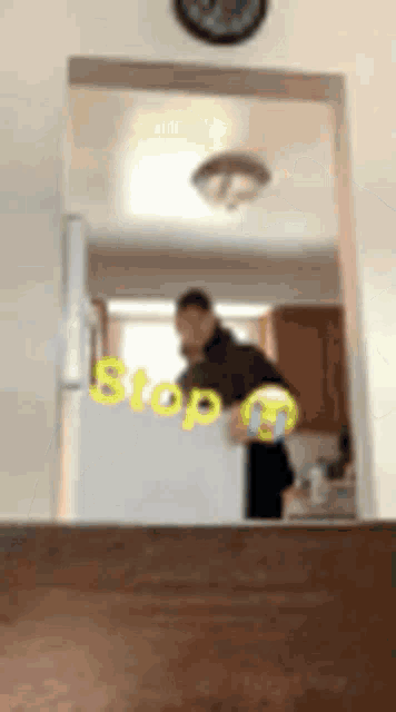 a man is standing in front of a refrigerator with the word stop written on it