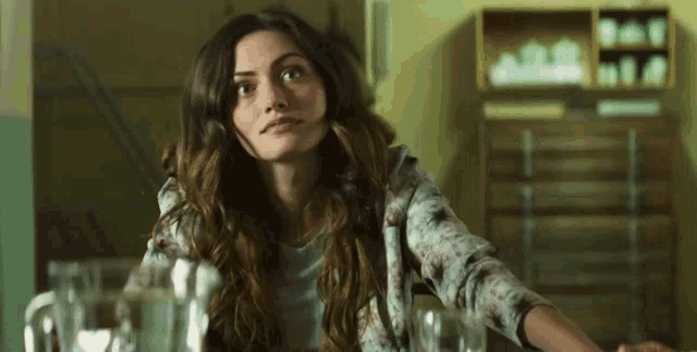 a woman with long hair is sitting at a table looking up