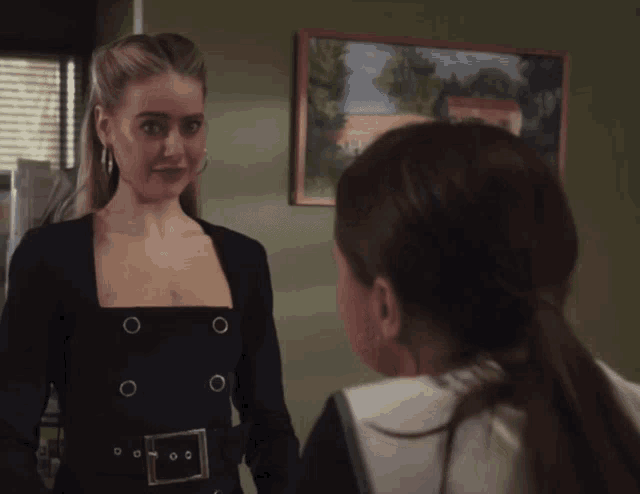 two women are standing next to each other in front of a painting on the wall