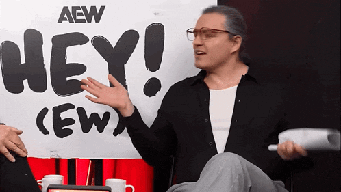 a man is sitting in front of a sign that says hey crew