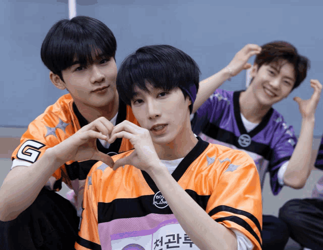 a boy wearing a jersey with the letter g on it makes a heart with his hands