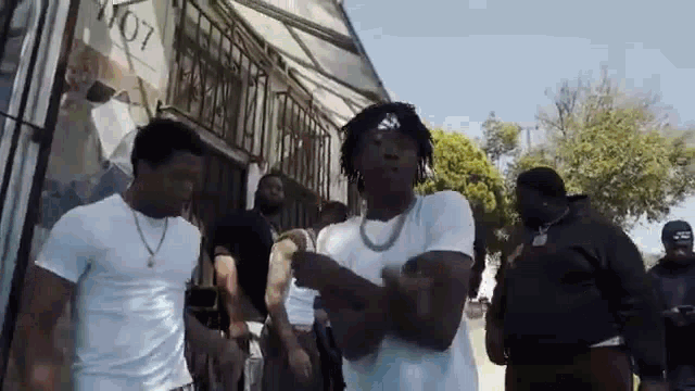 a group of men are standing in front of a building and dancing .