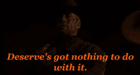 a man in a cowboy hat is holding a gun with the words " deserve 's got nothing to do with it " below him