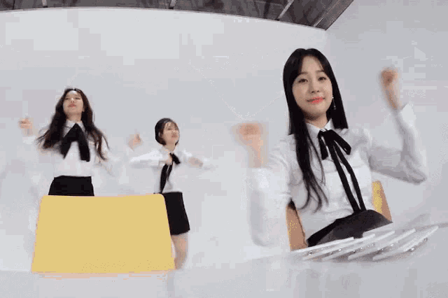 a group of girls are dancing together in a room while sitting at a table .