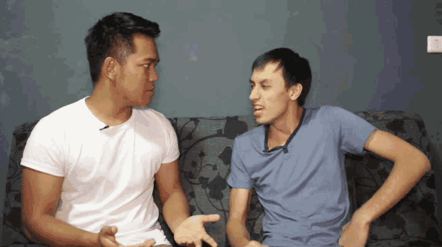 two men sitting on a couch having a conversation