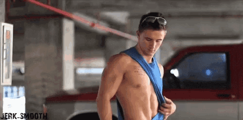 a shirtless man is standing in front of a red truck .