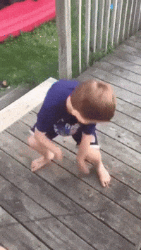a young boy is standing on a wooden deck