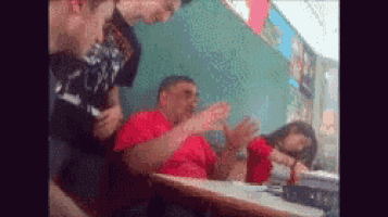 a man in a red shirt is sitting at a table with two other men