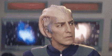a man with a white head and gray hair is standing in front of a television .