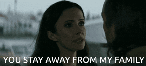 a woman is looking at a man with the words `` you stay away from my family '' written on the bottom .