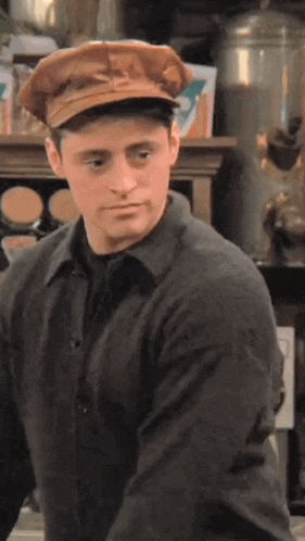 a man wearing a hat and a sweater is standing in front of a counter .