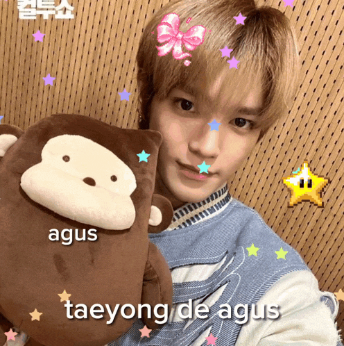 a young man holding a stuffed monkey with the name taeyong de agus written on the bottom