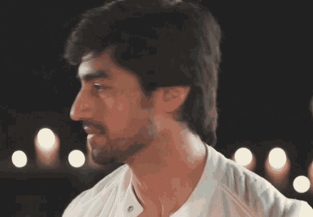 a close up of a man 's face with a beard and a white shirt
