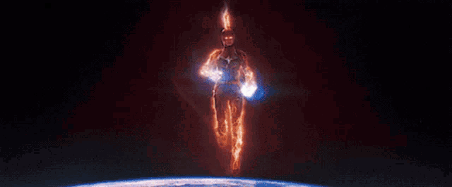 captain marvel is flying through the air in a dark room with a lot of light coming out of him .