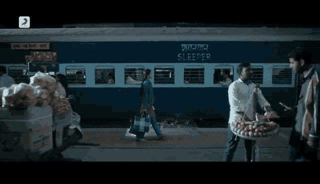 a man selling vegetables in front of a train that says sleeper