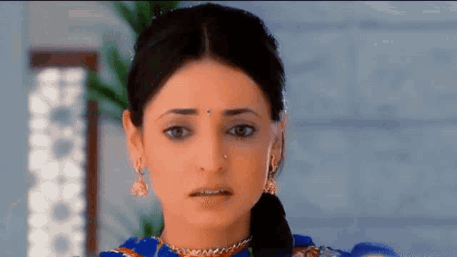 a woman with a nose ring is wearing a blue dress