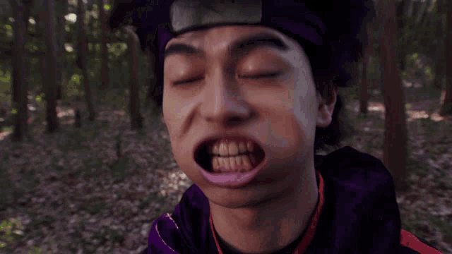 a man wearing a purple headband is making a funny face in the woods