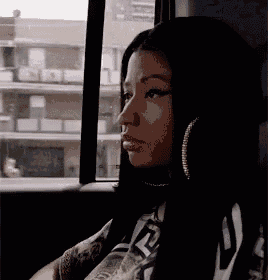 a woman wearing hoop earrings is sitting in a car looking out the window .