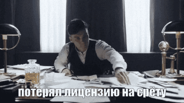 a man sits at a desk with a bottle of whiskey in front of him and says " потерял лицензию на срете "