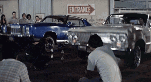 a group of people are working on a car in front of a sign that says entrance