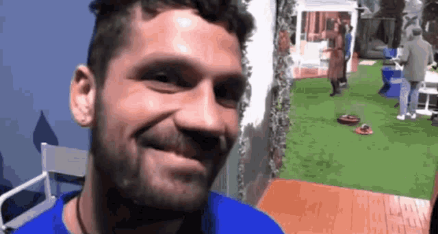 a man with a beard and a blue shirt is smiling